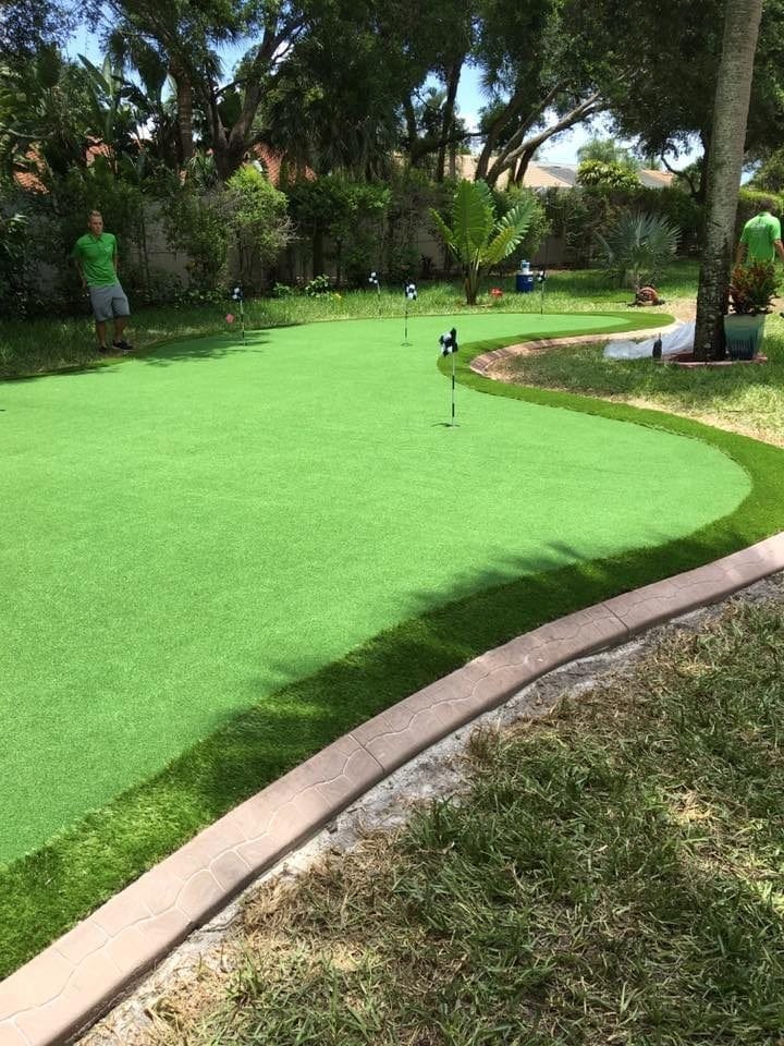 A well-maintained mini golf course with green artificial turf and a curved concrete border.