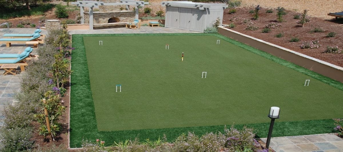 A green cricket field with players in action on a sunny day.