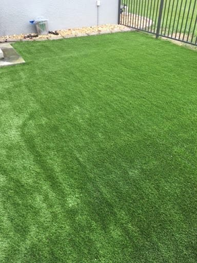 A backyard putting green surrounded by rocks and mulch.