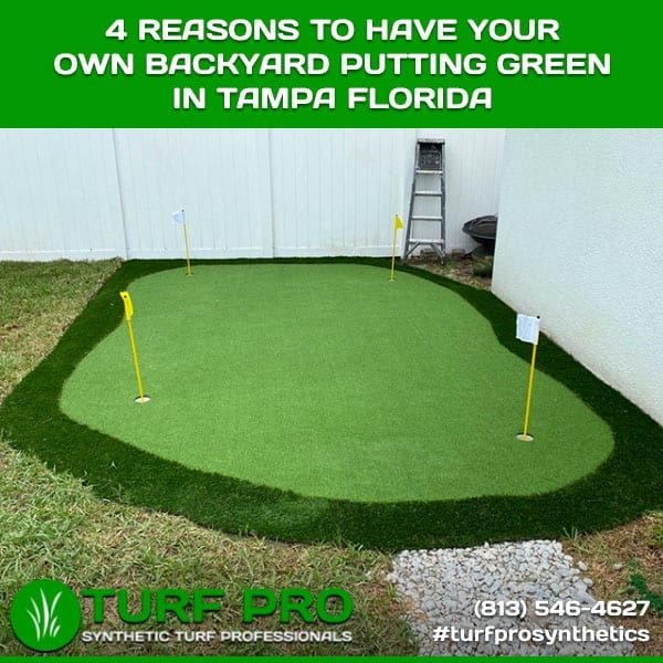A backyard green for putting practice with two flags and a white fence.