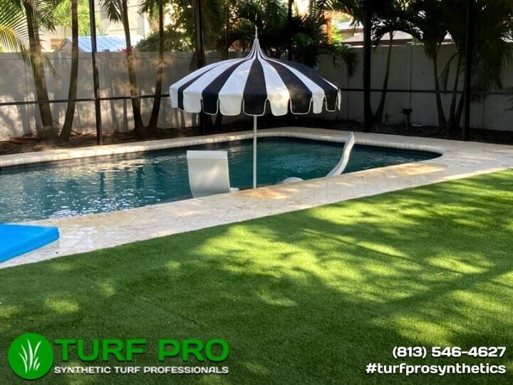 Backyard pool area with artificial turf and a black-and-white umbrella.