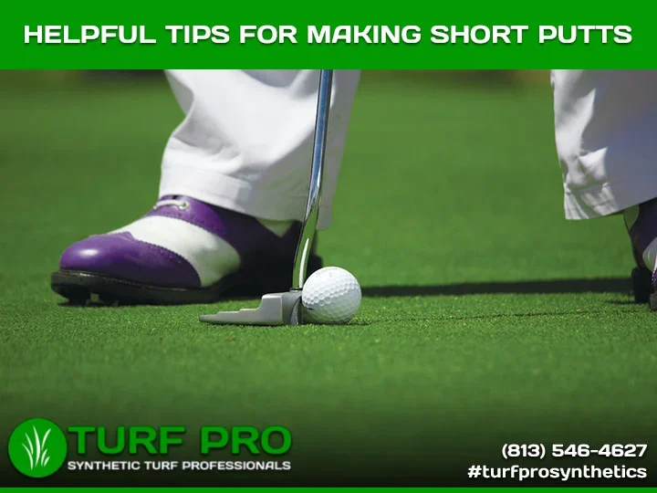 Close-up of a golfer's feet and putter preparing to putt on green turf.