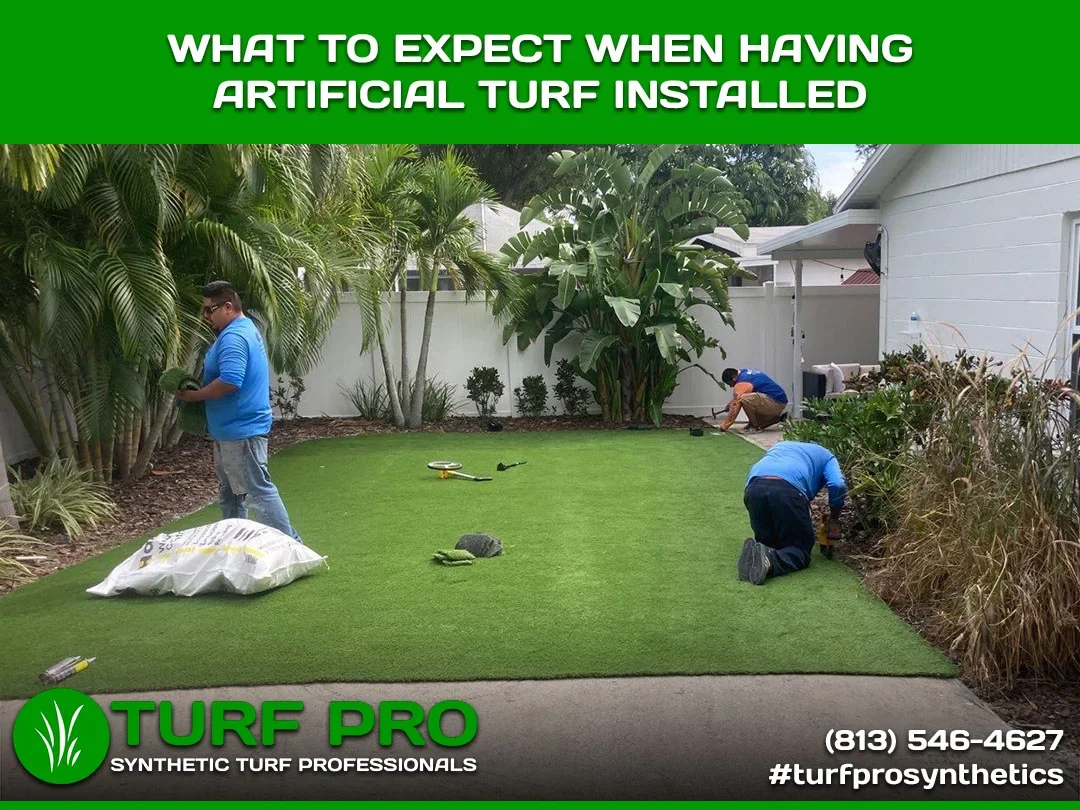 Workers installing artificial turf in a backyard garden.