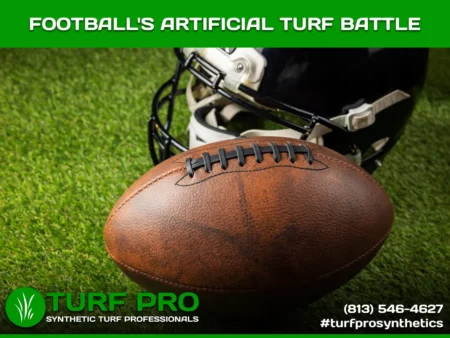 Close-up of a football on artificial turf with a helmet in the background.