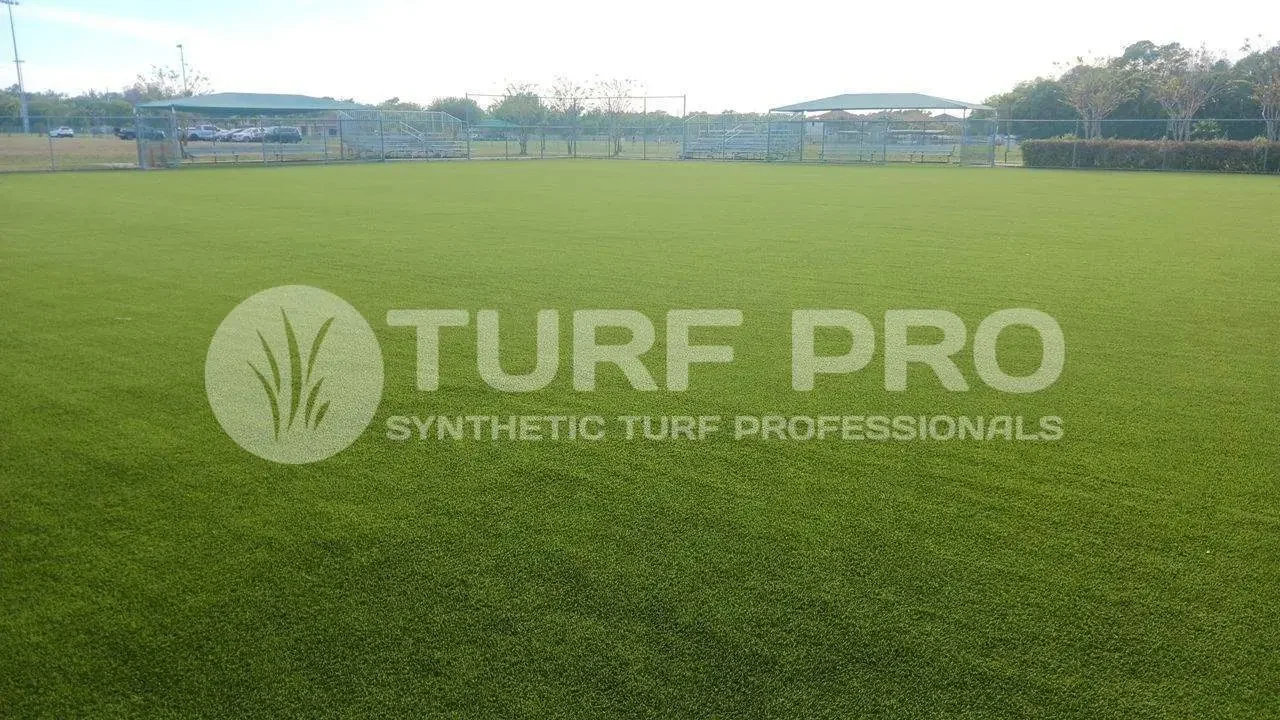 A large field of lush, green synthetic turf under a cloudy sky.