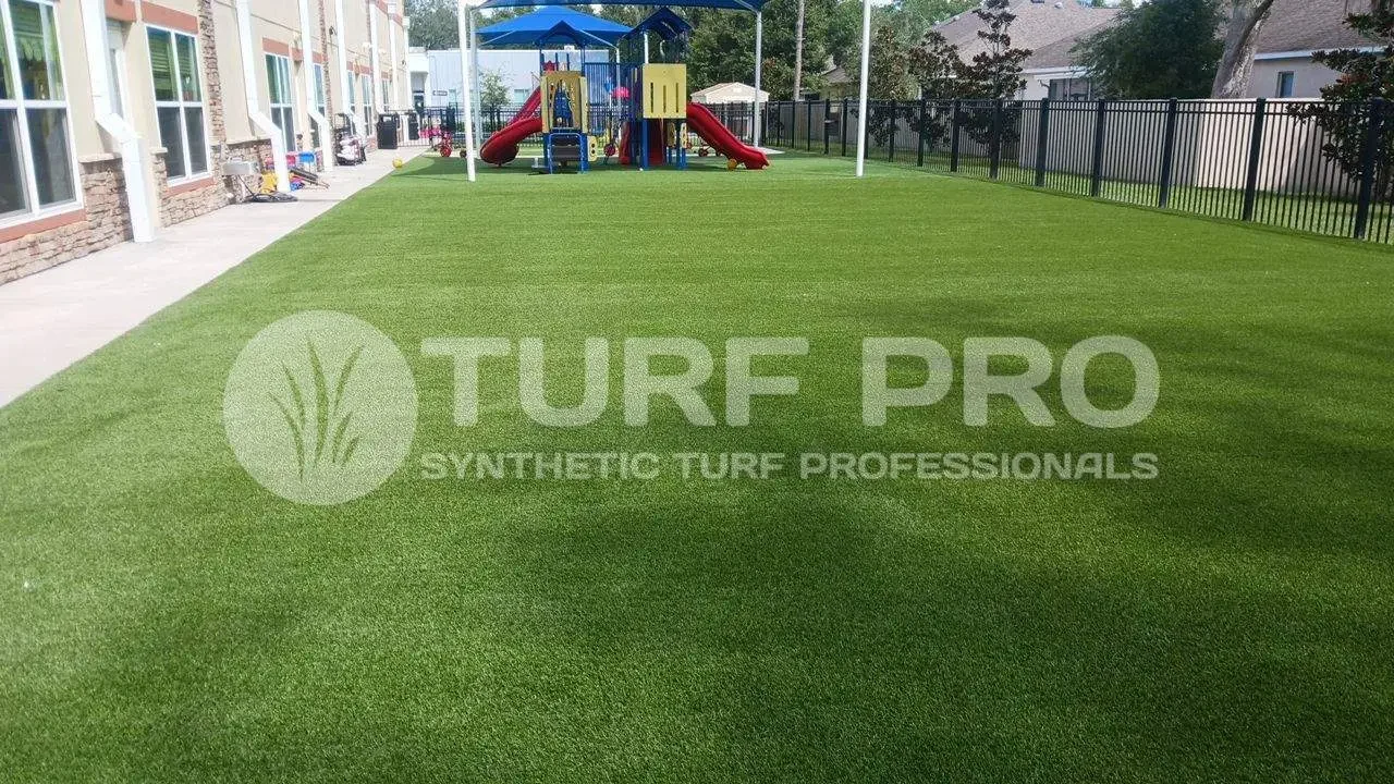 Bright green synthetic turf playground with slides and climbing structures.